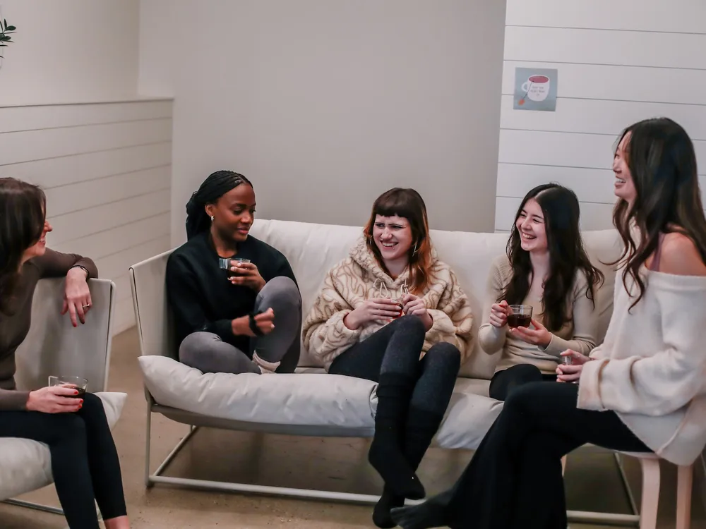 Members sitting together and chatting on the studio lounge couch.