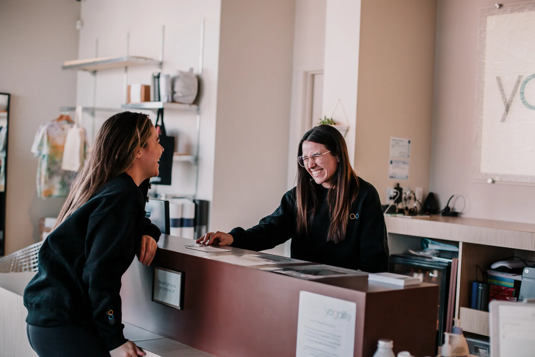 Two people smiling at each other across the studio reception counter.