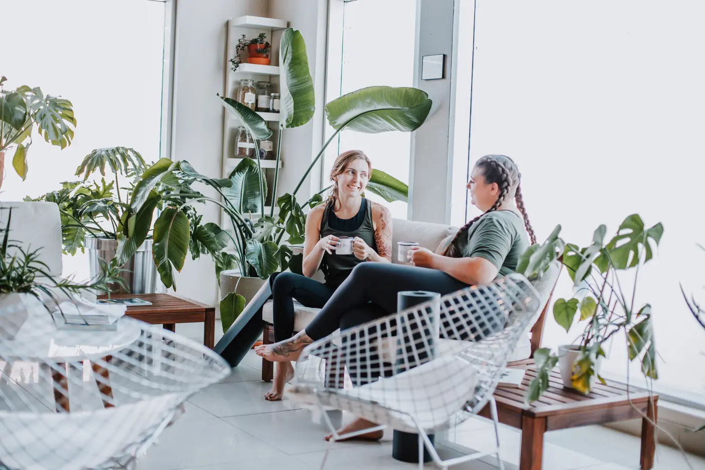 Two students relaxing in the plant-filled Yogalife South lounge.