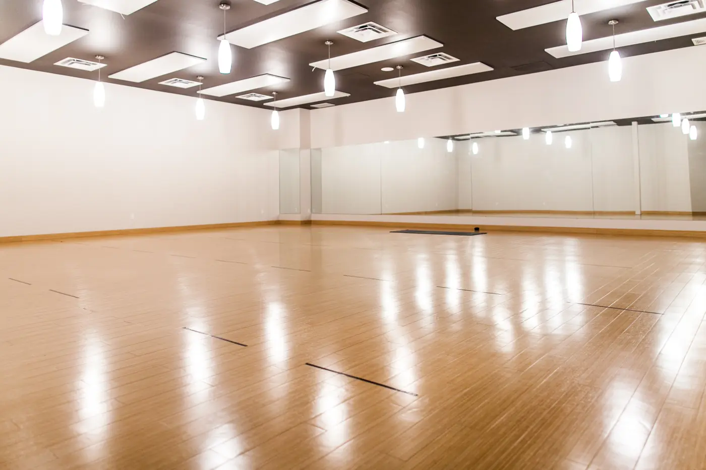 An empty Yogalife South practice room with wood floors and bright lighting.
