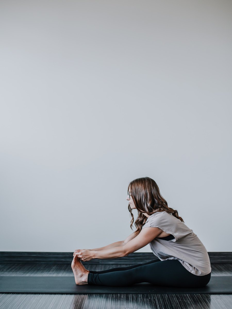 Megan Whitton seated in a forward fold on a mat at Yogalife
