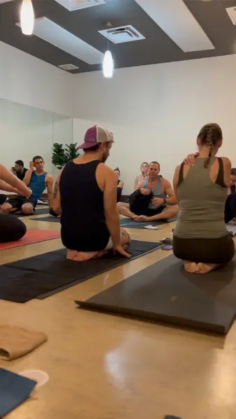 Students sitting back on their mats while a teacher talks the room through what's coming.