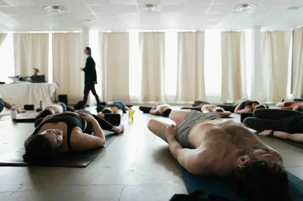 A room full of students resting on their backs in savasana during a Slow Sunday class.