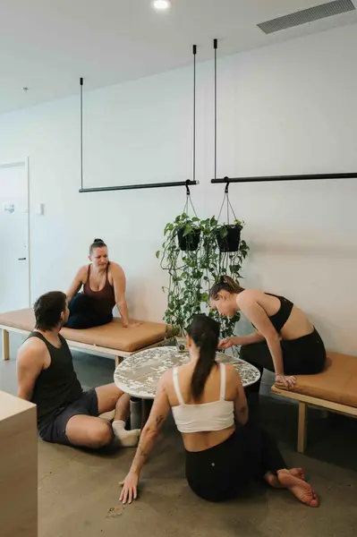 A teacher offering a gentle hands-on adjustment while others rest on their mats.