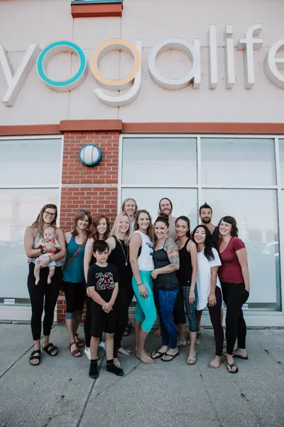 The Yogalife team gathered outside the studio under the sign, one of them holding a baby.