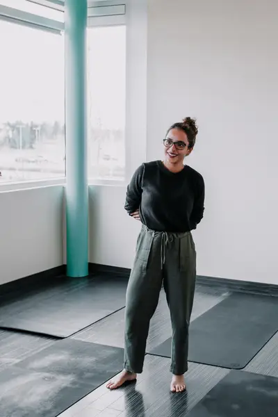 A teacher standing barefoot in the empty studio before class.