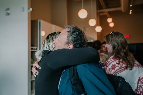 Two members hugging in the middle of a busy studio lobby.